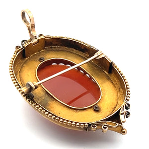 This vintage, oval-shaped Victorian 14kt yellow gold-toned brooch features a center carved agate portrait of a lady cameo, set in a decorative frame. The backside boasts a pin clasp and a loop for optional use as a pendant, highlighted by intricate metalwork and bead detailing around the border, evoking the elegance of Victorian jewelry.