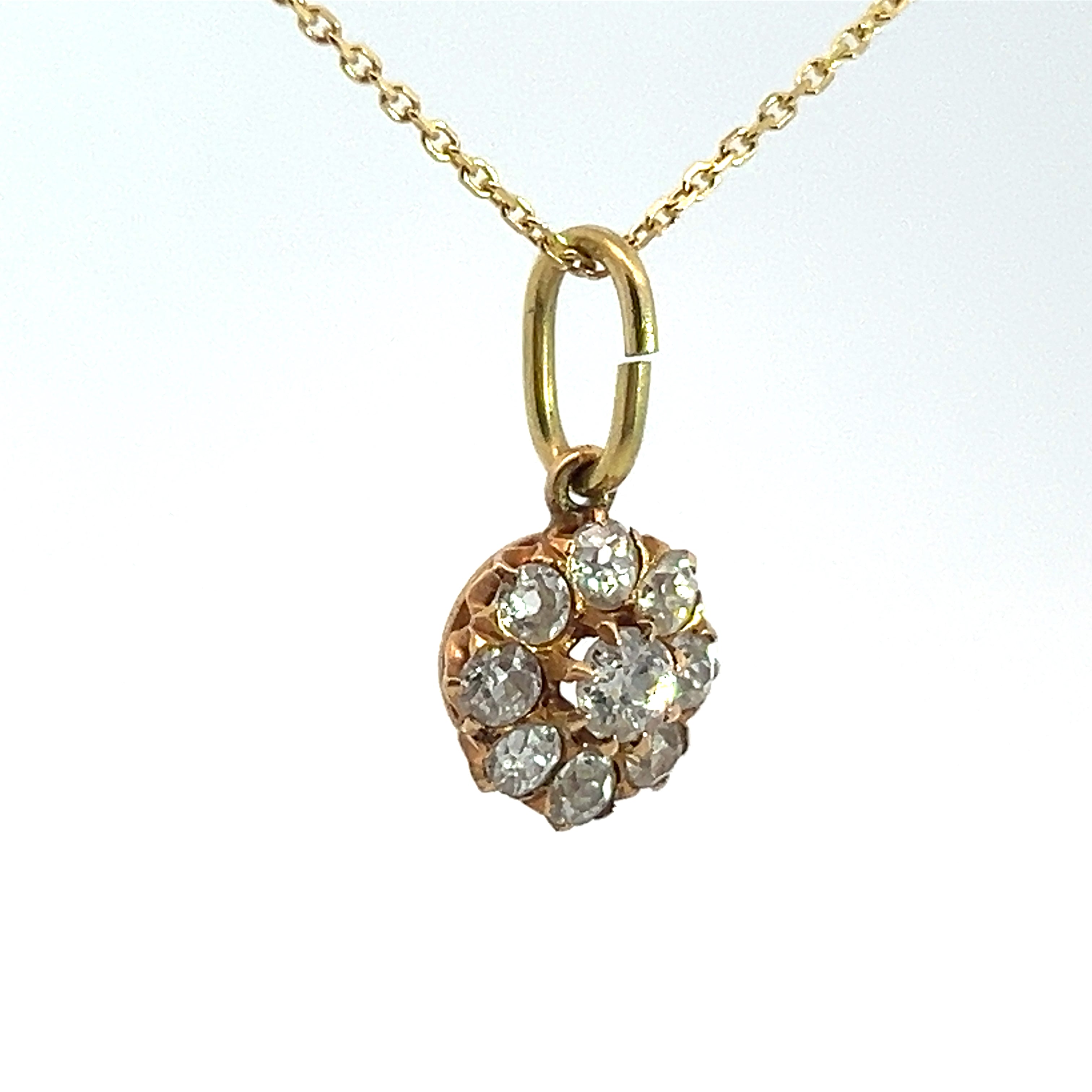 A Victorian 14kt yellow gold necklace showcasing a pendant adorned with a cluster of nine small, round old mine cut diamonds totaling 1.16 carats and arranged in a charming flower-like design. The timeless pendant is suspended elegantly from a delicate gold chain, all set against a white background.

