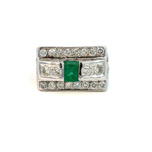 Load image into Gallery viewer, A striking Late Century 14kt white gold ring featuring a central 1ct emerald-cut emerald, flanked by two smaller diamonds. The broad band is adorned with rows of small diamonds on the top and bottom edges, contributing to its ornate design. This Emerald and Diamond Ring, set against a plain white background, showcases a total diamond weight of 5.70 carats in round brilliant cuts.
