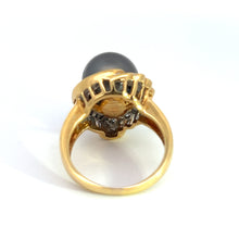 Load image into Gallery viewer, The &quot;Mid Century 14ktyg Black Pearl + 1.25ct diamond ring&quot; displays a large, dark gemstone in a prong setting. The intricate design of the setting is visible, with small decorative elements beneath the black pearl. The yellow gold ring is showcased on a white surface.