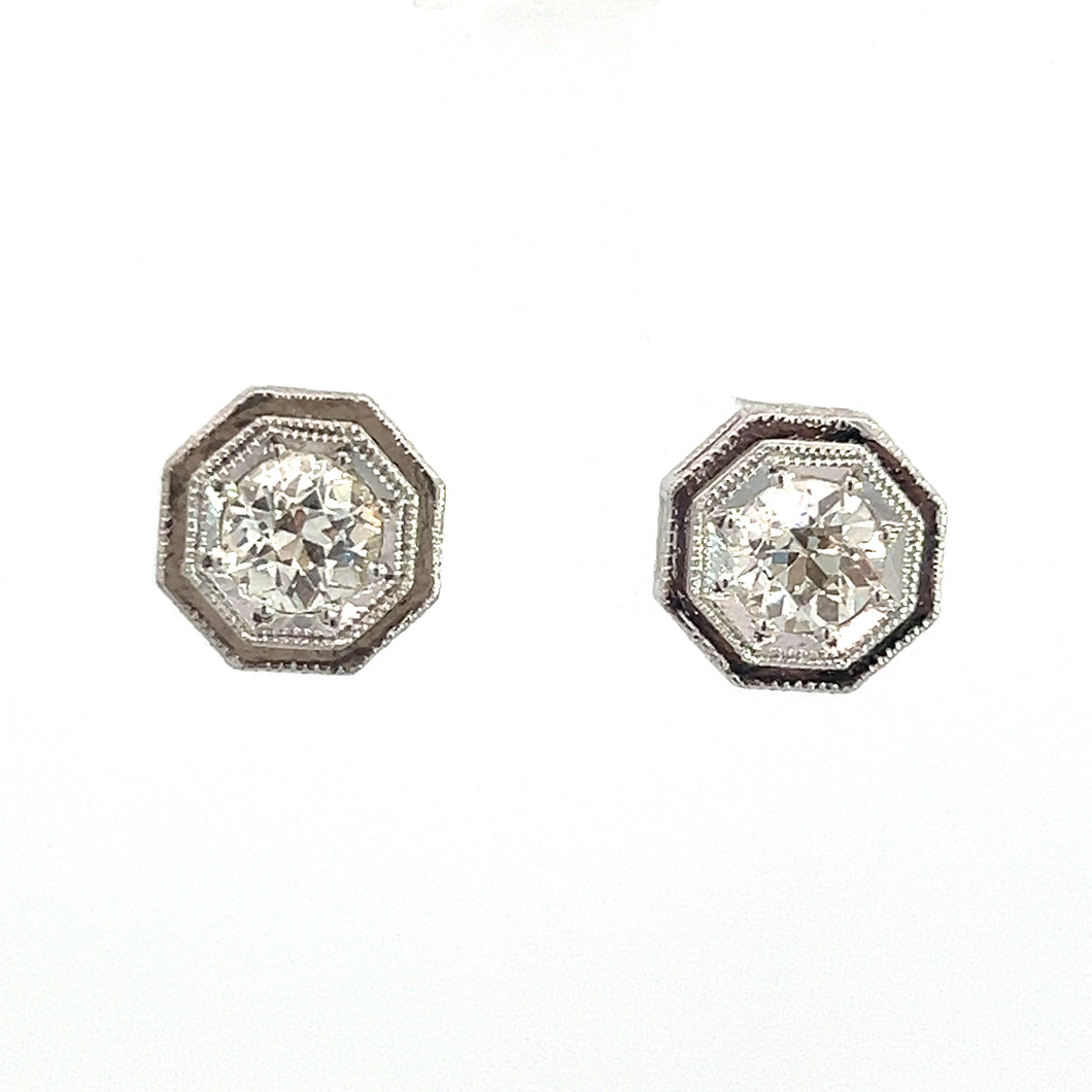 A pair of Art Deco Platinum Topped & 14kt White Gold 1.09ct Old European Cut Diamond Hexagon Frame Studs. Each earring features an old European cut diamond at the center, surrounded by intricate detailing on a plain white background.