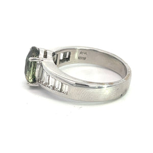 The Late Century Platinum ring showcases a stunning 3.03ct Alexandrite gemstone, mounted in a prong setting. The elegantly simple band is adorned with 1.28cttw of baguette-cut diamonds, providing sophisticated detail. This exquisite jewelry piece, known for its captivating color-changing properties, features fine engravings on the inner side of the band.