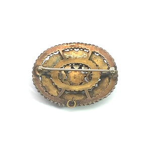 The Victorian Vermeil Oval Garnet Brooch is an intricately designed piece from the Victorian era, boasting a metallic gold finish. The back side showcases a pin mechanism for fastening. This vintage charm presents a textured, scalloped edge and a central circular pattern, radiating timeless elegance.