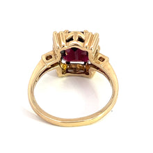 Load image into Gallery viewer, The Mid Century 14kt yellow gold ring features a stunning 4.80ct rectangular garnet at its center, complemented by .06cttw diamonds. The band and setting boast intricate detailing, highlighting the ring&#39;s elegant mid-century design, with the back view revealing the secure placement of the stone within an ornate gold framework.