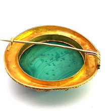 Load image into Gallery viewer, The Victorian 18ktyg Fancy Frame Malachite Brooch features a gold-toned setting that beautifully surrounds a circular green malachite stone at its center. It includes a pin and clasp mechanism on the back, which is visible in the provided image against a plain white background.