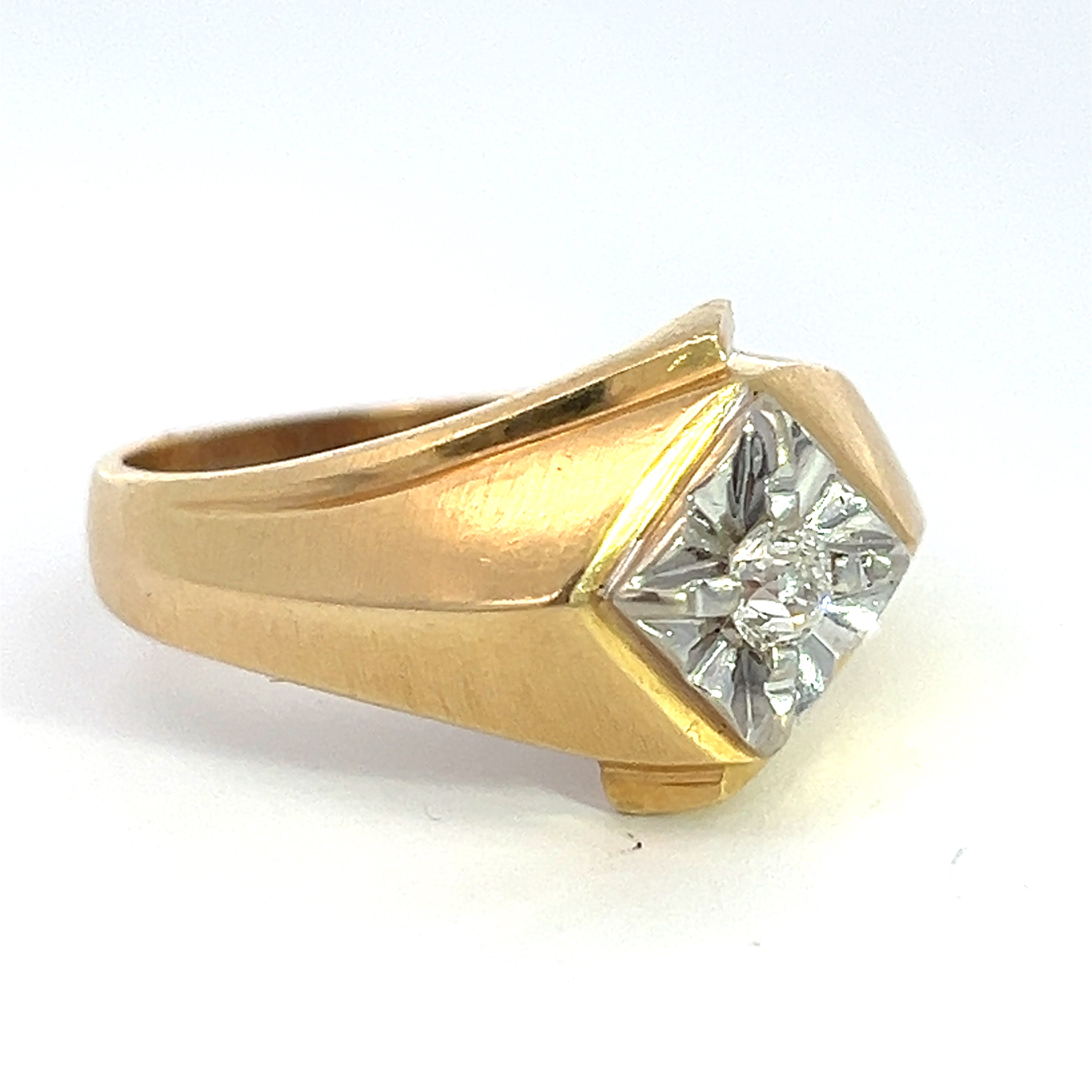 The "Late Century 14kt Two Tone Gold .25ct Old Mine Cut Diamond Ring" showcases a distinctive asymmetrical design. Its centerpiece, a small round old mine cut diamond, is set in a recessed geometric pattern adorned with silver-toned accents. The broad, smooth band features gentle curves that enhance its vintage appeal.