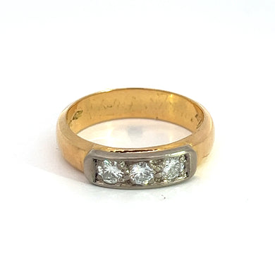 The Late Art Deco Plat/18ktyg .50ct Round Brilliant Cut Diamond Engraved band c.1911 features a rectangular bezel setting adorned with three round brilliant cut diamonds in a row. The ring exhibits some signs of wear and has developed a faintly scratched patina, which adds to its vintage charm. Set against a plain white background, the intricate Art Deco details of this piece are beautifully highlighted.