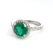 Load image into Gallery viewer, Introducing the Modern 18kt White Gold 1.80ct Emerald + .50cttw Diamond Ring, showcasing a stunning 1.80ct emerald at its center, encircled by a halo of small white diamonds totaling .50cttw. The band is elegantly adorned with additional small white diamonds on the sides, further enhancing its sophisticated and luxurious look.