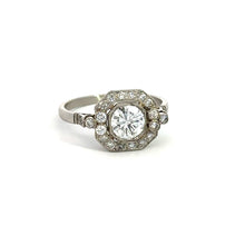 Load image into Gallery viewer, The Art Deco Platinum .80ct Round Brilliant Cut + 1.08cttw Diamond Ring showcases an elegant central round brilliant cut diamond encircled by smaller diamonds arranged in a geometric pattern. The band is simple, enhancing its sophisticated and classic look. The ring is displayed against a plain white background, emphasizing its beauty.