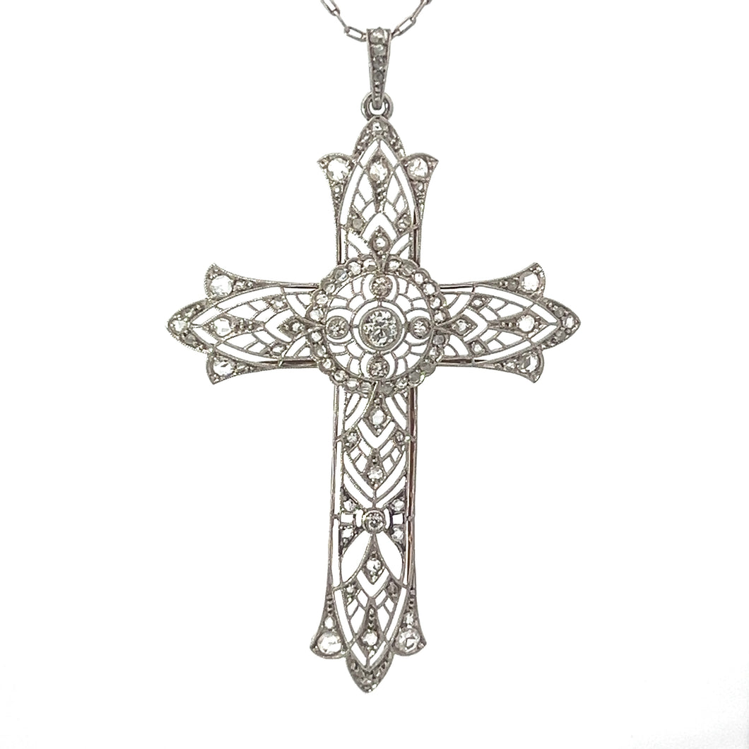 The Edwardian Platinum/18kt Yellow Gold 2.05cttw Old Mine + Rose Cut Diamond Filigree Cross showcases timeless beauty with its intricate filigree design. Featuring symmetrical patterns and delicate craftsmanship, this pendant hangs from a simple chain. The central part is adorned with a circular motif reminiscent of vintage romance, adding to its ornate appearance.