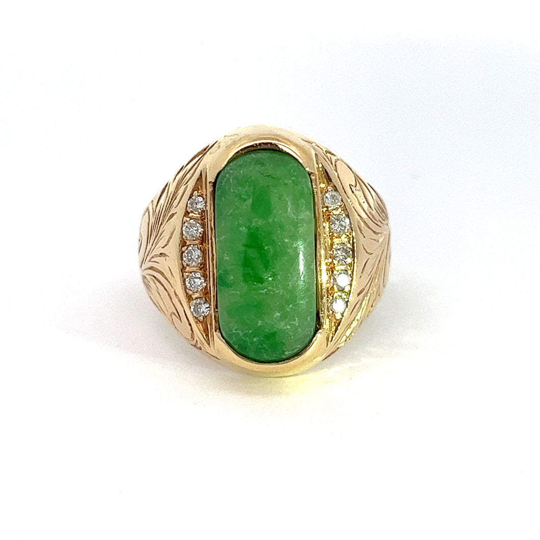 Introducing the Late Century 14kt Jade Diamond Ring: a masterpiece featuring an oval green marbled jade gemstone at its center, flanked by brilliant cut diamonds on both sides. The 14kt yellow gold band is adorned with intricate engraved patterns, adding an ornate touch to the elegant design. A plain white background beautifully highlights every detail of this exquisite piece.