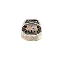 Load image into Gallery viewer, A Late Century Konstantino Sterling Silver &amp; 18kt Yellow Gold 5ct Emerald Cut Amethyst Ring shown from the underside, displaying intricate purple gemstone inlays. The inner sterling silver band has cut-out designs resembling teardrops, allowing the light to pass through the amethyst stones. The exterior design with 18kt yellow gold accents is not visible in this view.