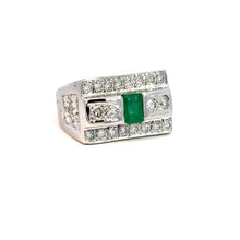 Load image into Gallery viewer, A stunning Late Century 14kt White Gold ring featuring a central 1ct emerald-cut emerald, flanked by round brilliant-cut diamonds totaling 5.70cttw. The edges of the ring are also elegantly adorned with smaller round white diamonds, all majestically displayed on a white background.