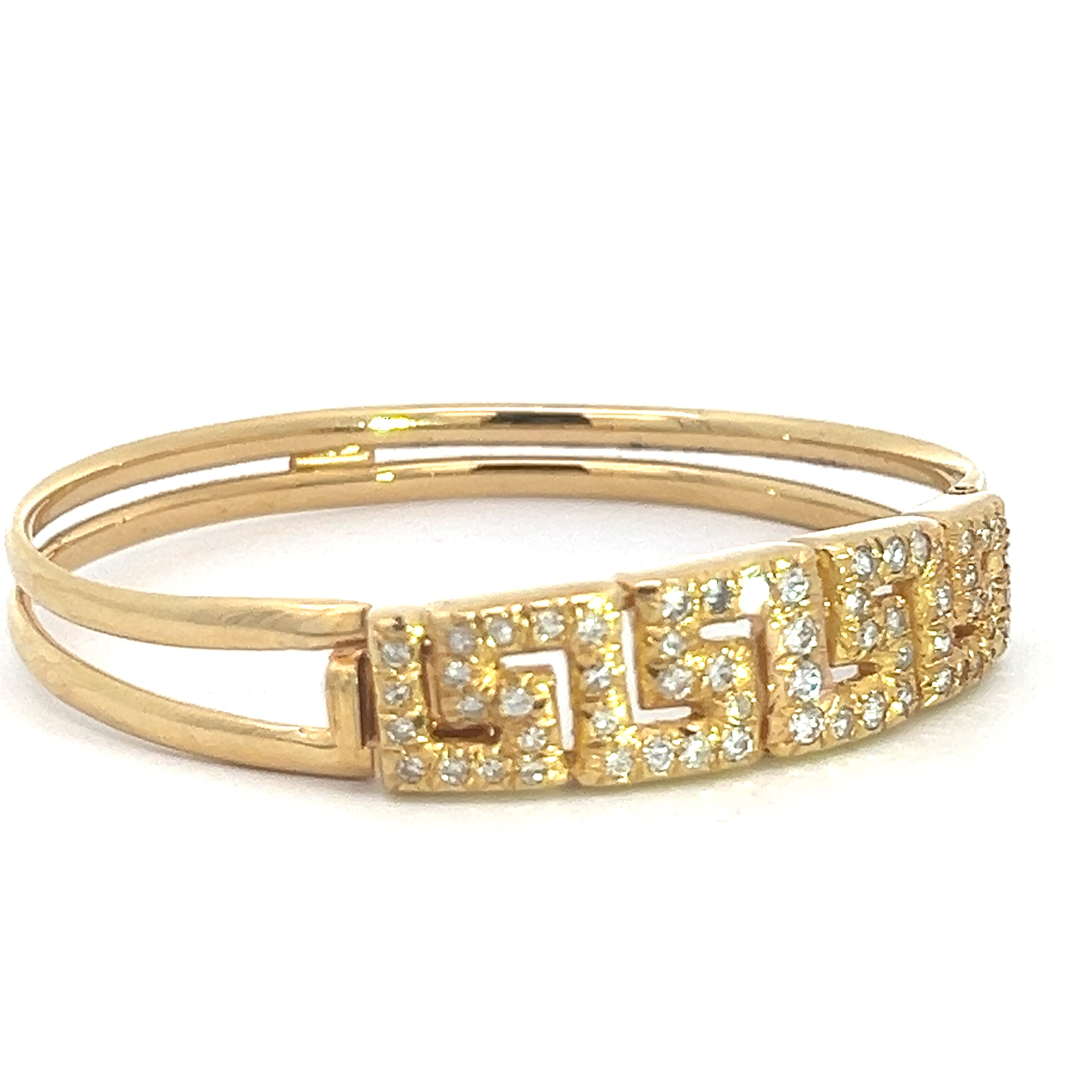 The Late Century 18ktyg 1.80cttw Greek Key Diamond Bangle Bracelet is showcased against a white background, highlighting its geometric design and shimmering small diamonds. This exquisite 18k yellow gold bracelet features two slender, smooth gold bands that converge at a central section intricately detailed in the Greek Key pattern and adorned with sparkling gemstones, evoking the elegance of a Late Century diamond bangle.