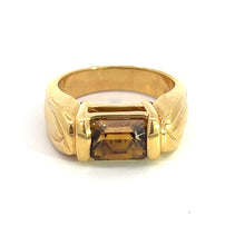 Load image into Gallery viewer, The Late Century 18ktyg 3ct Cognac Zircon ring showcases a stunning rectangular brown gemstone set in the center of its 18kt yellow gold band. The smooth band is adorned with subtle engraved detailing on either side of the stone, presenting a vintage luxury piece that stands upright on a plain white background.