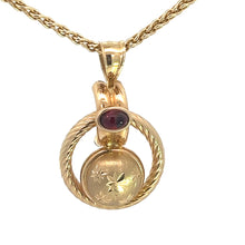 Load image into Gallery viewer, A Victorian 14kt yellow gold necklace featuring a .50ct cabochon garnet set in a gold casing above a diamond-cut disc with a floral pattern. The pendant has a dual-hoop design, with the garnet set at the top loop, and it hangs from an 18-inch twisted rope-like chain.