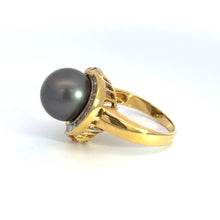 Load image into Gallery viewer, A yellow gold ring, named the Mid Century 14ktyg Black Pearl + 1.25ct diamond ring, showcases a large, dark pearl set in an ornate design. The lustrous black pearl is complemented by a gold band with intricate detailing and an array of sparkling diamonds totaling 1.25 carats, exuding elegance and luxury. This exquisite piece is presented against a clean, white background.