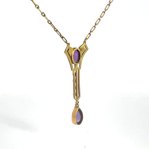 The Victorian 14kt Yellow Gold 3.50cttw Amethyst Pearl Lavalier Necklace features a geometric pendant adorned with purple stones. The elongated design showcases a drop-shaped amethyst at the bottom, complemented by a smaller rectangular amethyst near the top. The chain is composed of small, oval links, exuding the elegance typical of Victorian jewelry.